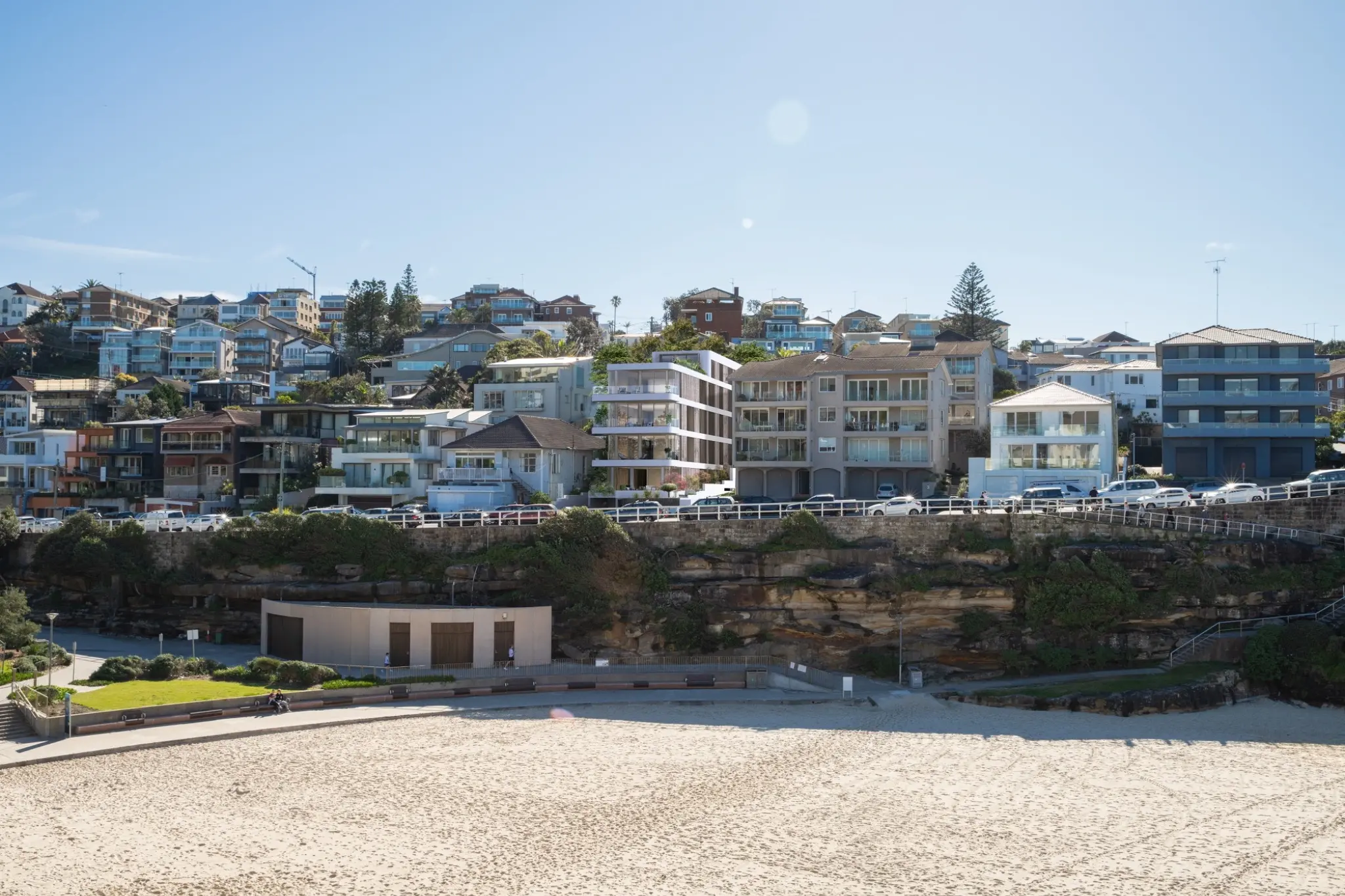 Coastal apartment photomontage for Pacific Avenue, Tamarama, placing the proposed multi-residential design accurately within the existing hillside neighbourhood and beachfront context. Wide coastal architectural photomontage of a contemporary apartment building on Pacific Avenue in Tamarama integrated into the existing beachfront streetscape